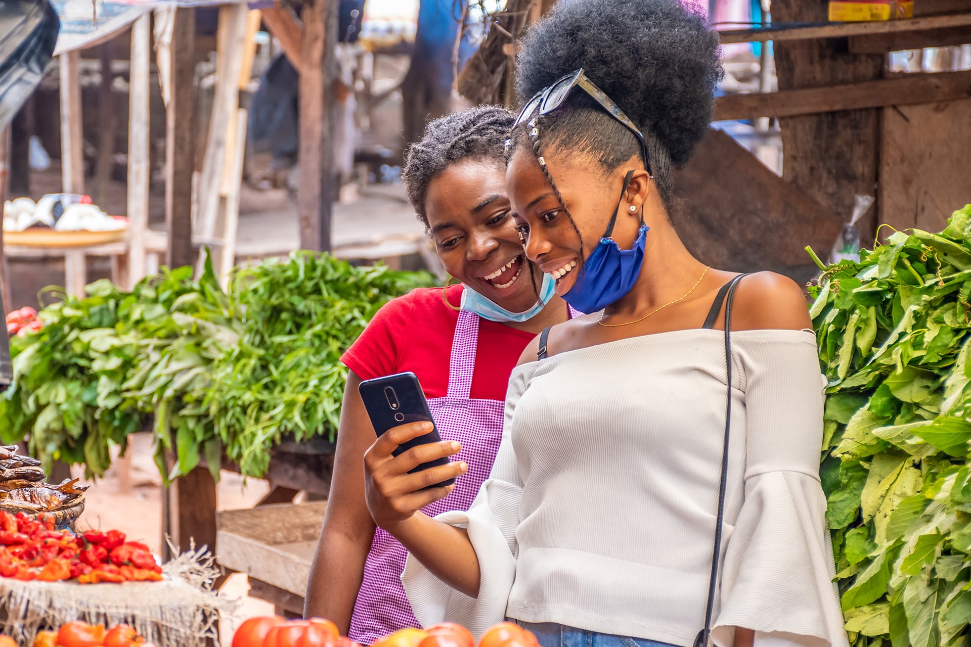 Commerçantes consultant un téléphone mobile sur un marché béninois